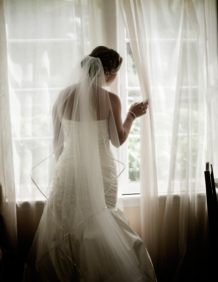 Bride looking out a pretty window watching her guests arrive at Camrose Hill Farm in Stillwater, MN.