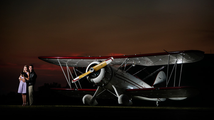 Sunset engagement portrait of a cute couple and their puppy Harper and a classic biplane. Image taken at the Flying Cloud Airport in Eden Prairie, MN.