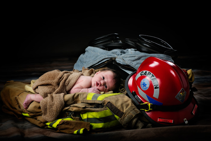 Newborn baby photos of baby girl and dad's firemen gear.