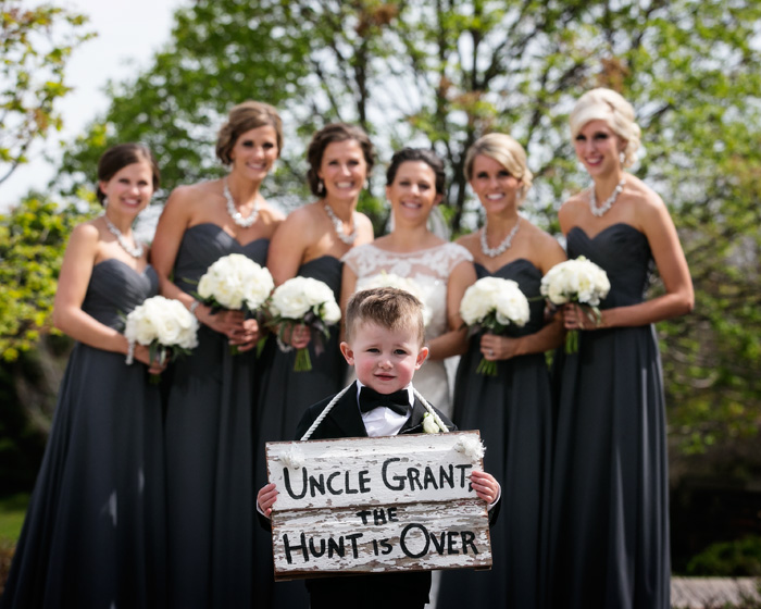 Cute ringbearer holding a sign at a Rush Creek Golf Course wedding.