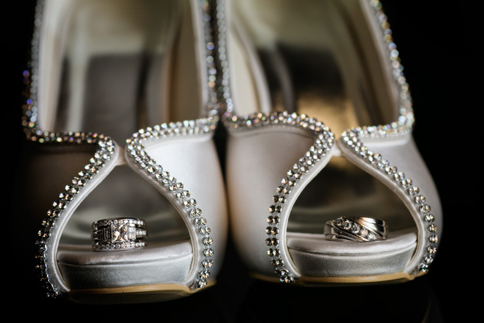 Close up wedding details of brides shoes with wedding rings.