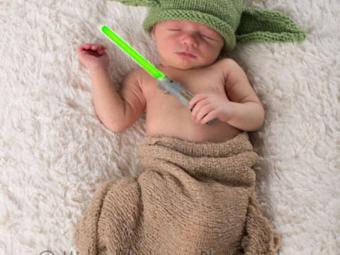 Newborn baby boy dressed as "Yoda" from Star Wars and sporting a light saber too!