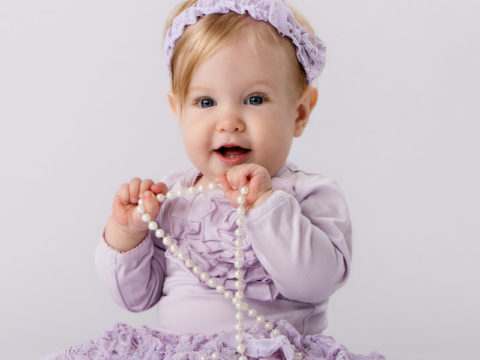 9 month old baby portraits of a cute little girl playing with a pearl necklace.