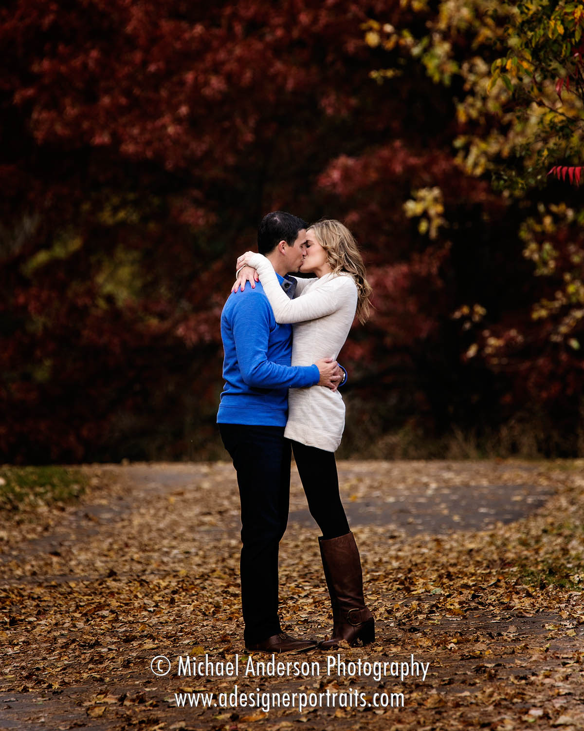 A cute couple kissing on a trail during their fall color Colby Lake Park  engagement portraits. - Michael Anderson Photography