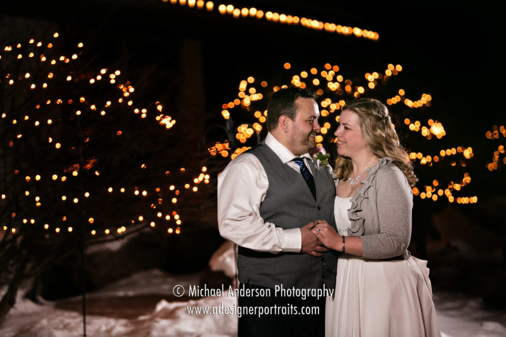 A fun night shot of a bride & groom in front of the pretty holiday lights at their Crystal Lake Golf Club wedding in Lakeville, MN.