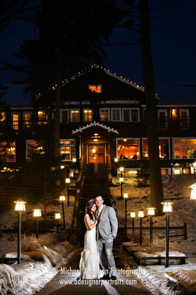 A pretty destination wedding photograph of a bride and groom taken at night with the historic Grandview Lodge in the distant background.