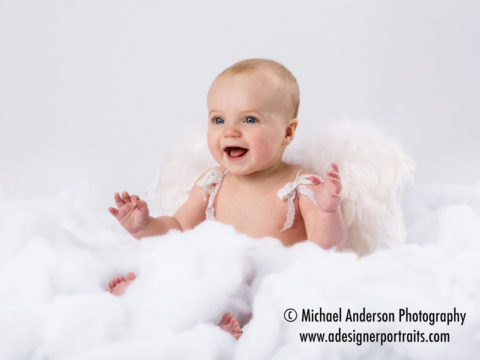 Six month portraits of a cute baby girl dressed in angels wings.