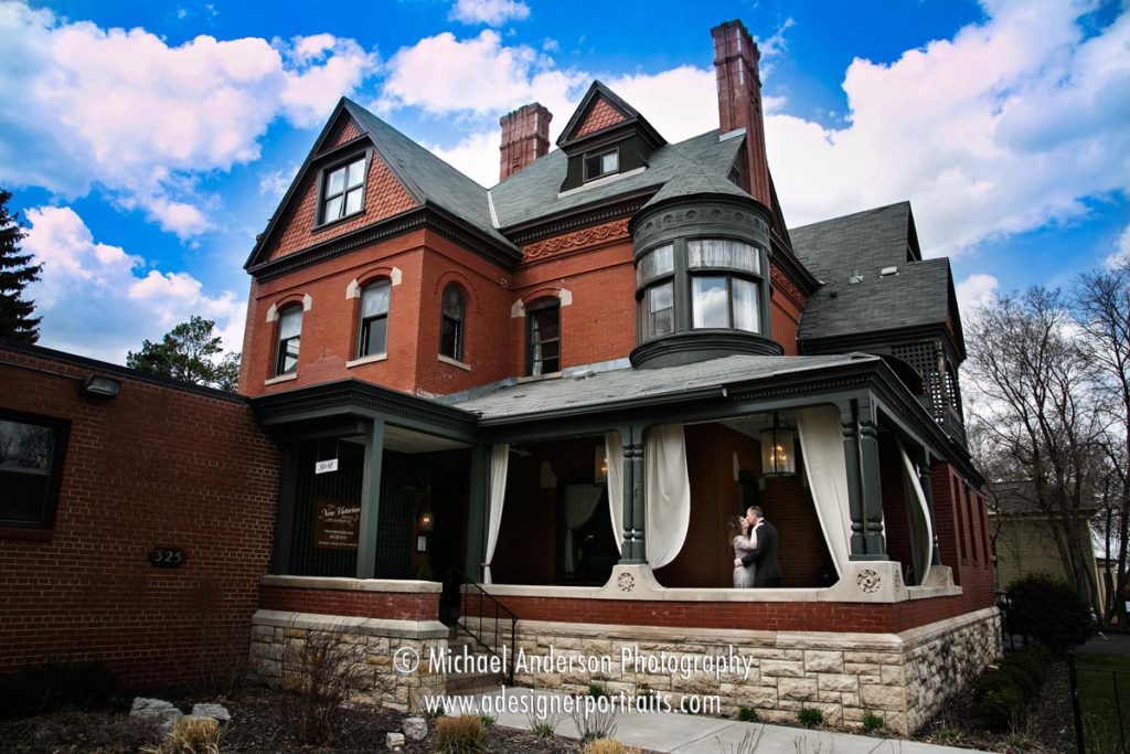 Wide angle image of a bride & groom on the porch at The New Victorian Mansion B&B in Saint Paul, MN.