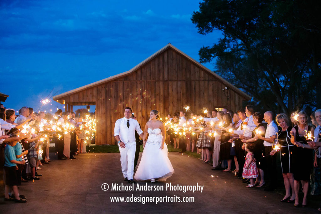 Bride & groom walking while their guests wave sparklers. Image taken at The Hitchin' Post in New Richmond, WI.