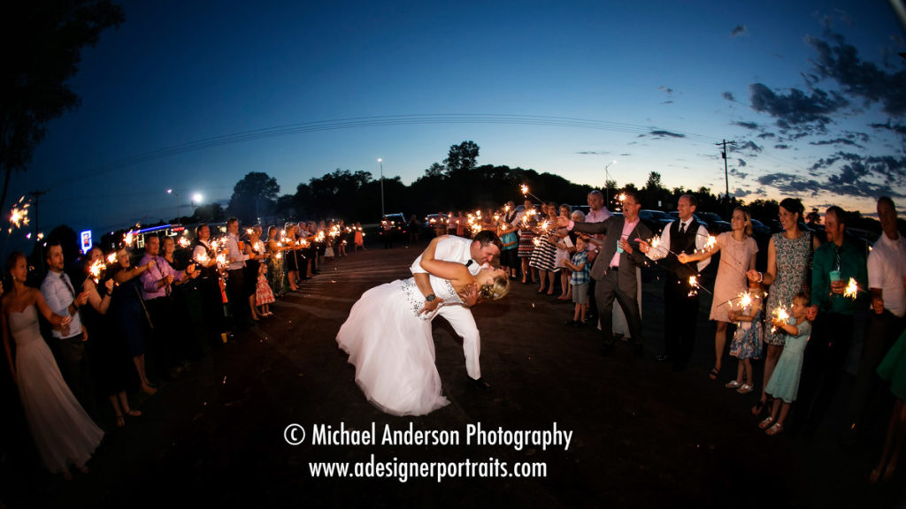 Bride & groom kissing while their guests wave sparklers. Image taken at The Hitchin' Post in New Richmond, WI.