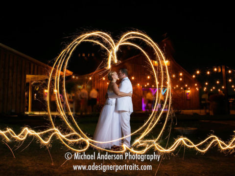 Wedding light painting photography of a bride & groom kissing in a heart made from sparklers. Image taken at The Hitchin' Post wedding of Jay & Vanessa in New Richmond, WI.