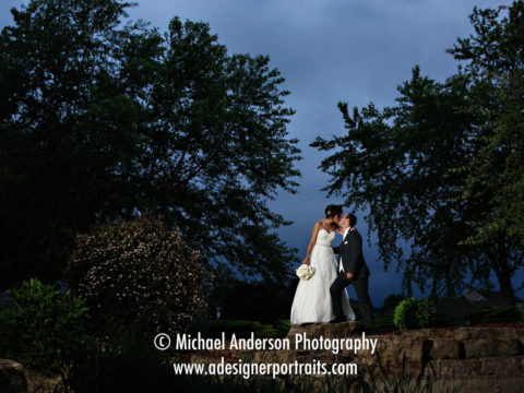 Beautiful wedding photograph of a bride and groom kissing on a stone bridge. Image taken at night at TPC Twin Cities in Blaine, MN.