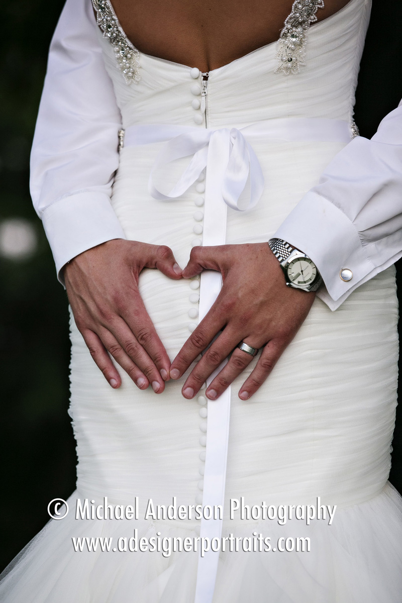 Fun wedding photo of a groom making a heart shape on his bride while hugging the bride. Image taken at Brackett's Crossing Country Club in Lakeville, MN.