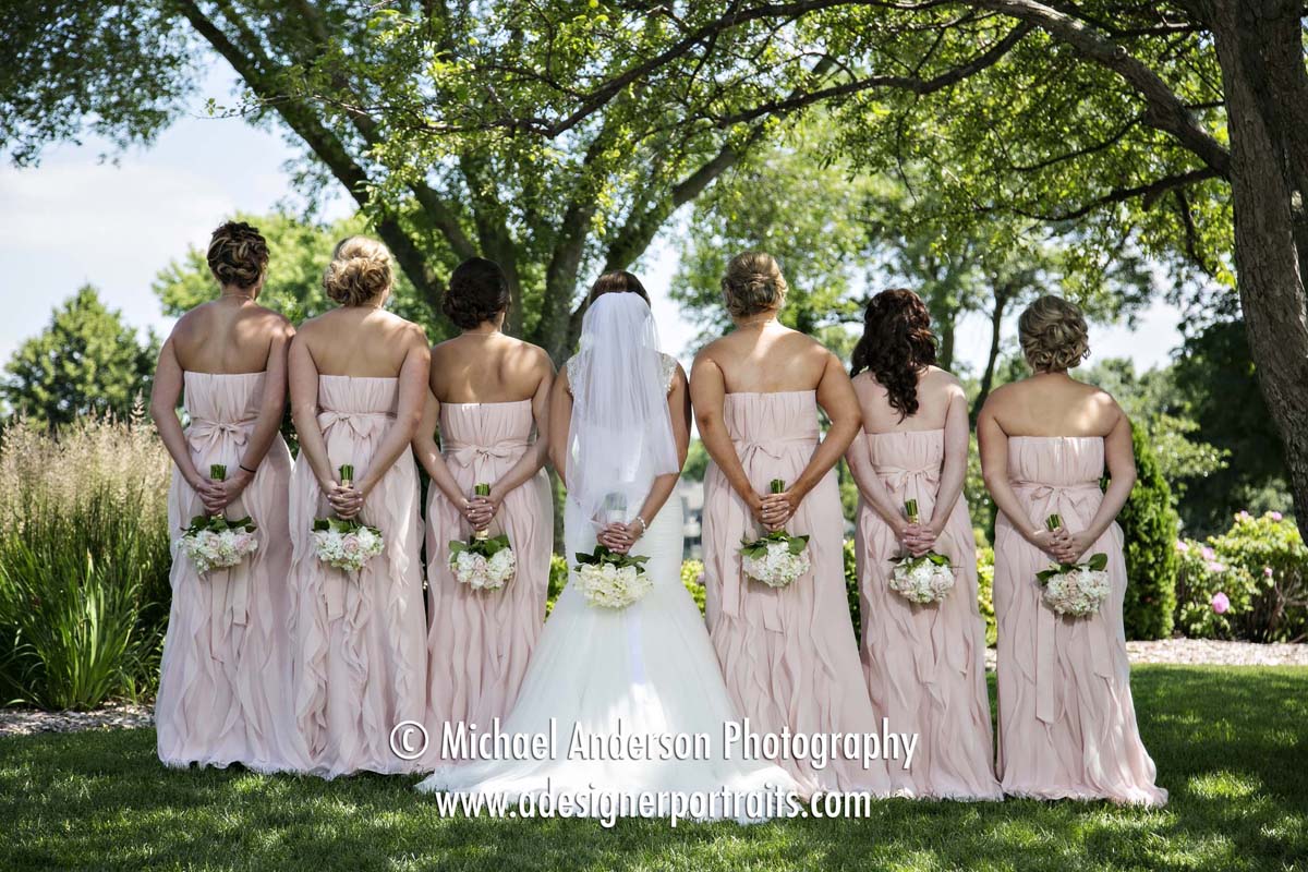 Wedding photo of the back of the brides & bridesmaids dresses and bouquets taken at Brackett's Crossing Country Club in Lakeville, MN.