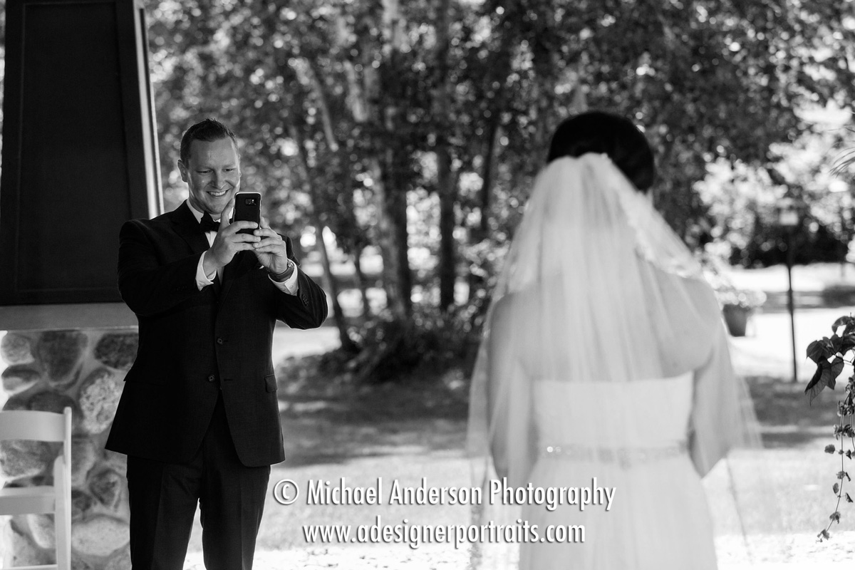 Groom takes a photo of his bride with his cell phone just after their first look. Wedding photo taken at their Grand View Lodge wedding in Nisswa, MN.