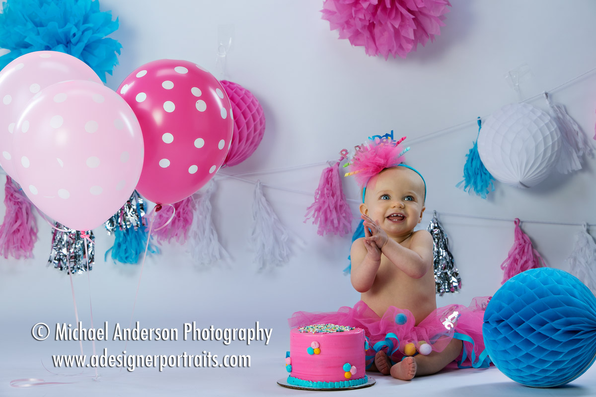 Cute one year old baby girl portraits taken in studio. Cute baby girl with cake, balloons and party decorations too!