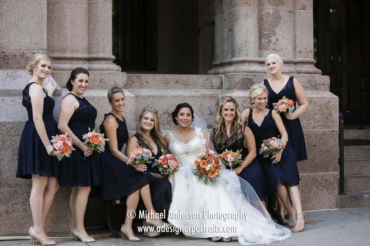 A cute, candid pose of a bride and her bridesmaids on a park bench just outside the Landmark Center in Saint Paul, MN.
