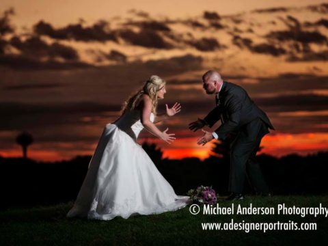Wedding photography at The Wilds Golf Club Prior Lake MN. Bride & groom (a former wrestler) strike a wrestling pose in front of a beautiful sunset at their wedding reception at The Wild's Golf Club in Prior Lake, MN.