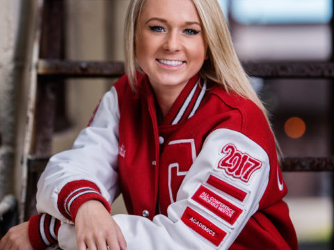 A traditional senior portrait of a girl wearing her Centennial High School letter jacket. Image taken on an old fire escape in Two Harbors, MN.