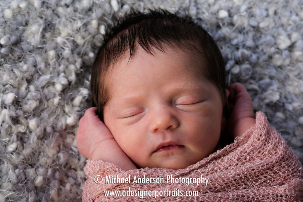 A cute studio portrait of a beautiful newborn baby girl wrapped up and sleeping.