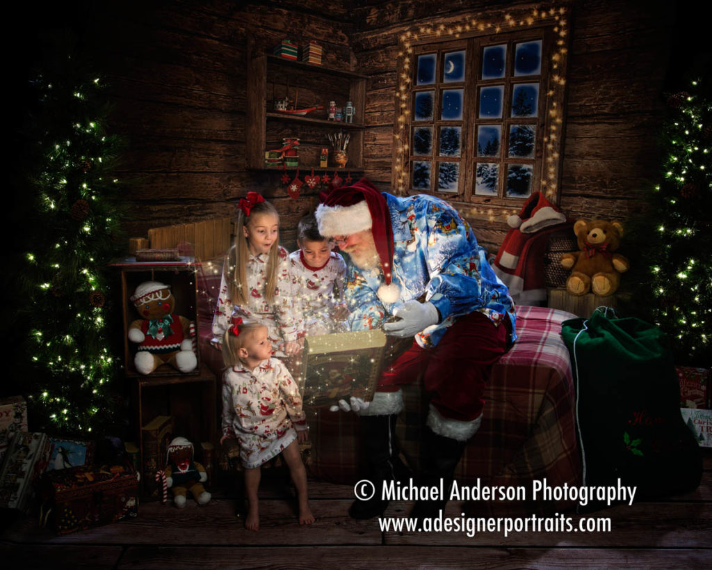 Santa Claus reads a bedtime story to three siblings in their Christmas pajamas. Image taken during their 2016 Heirloom Santa Claus Portraits for Cystic Fibrosis.