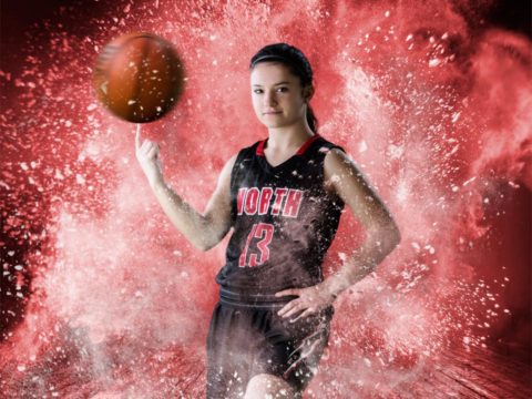 A girls basketball green screen composite of a North Saint Paul Varsity Girls basketball player in a powder explosion on a wood gym floor.