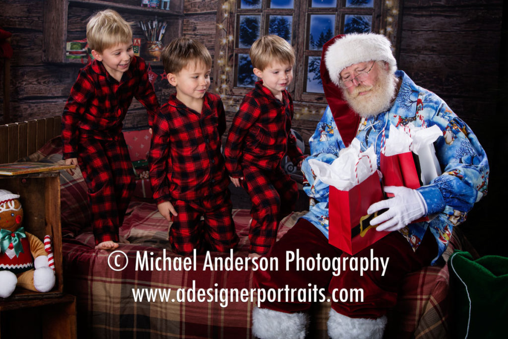 Santa Claus gives gifts to three boys during their Heirloom Santa Portraits.
