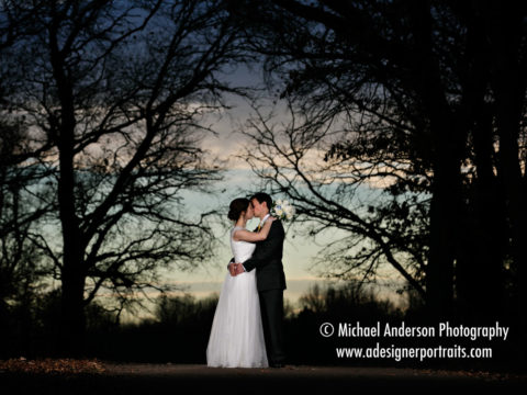 A pretty wedding day photo of a bride & groom kissing at sunset on a pathway in Long Lake Regional Park in New Brighton, MN. Wedding photo taken after their wedding at Our Savior's Lutheran Church in Circle Pines, MN.