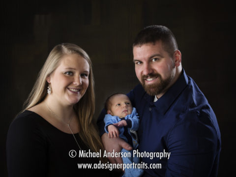 A family studio portrait with their one week old newborn baby boy.