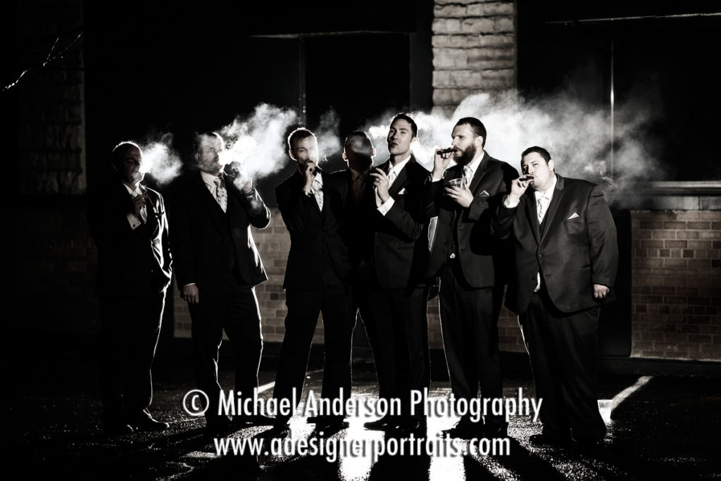 The groom and & his groomsmen smoking cigars in the light rain outside his Profile Event Center wedding reception in Minneapolis, MN.