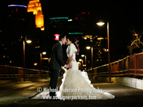 The bride & groom share a nighttime kiss on the historic Stone Arch Bridge in Minneapolis, MN.