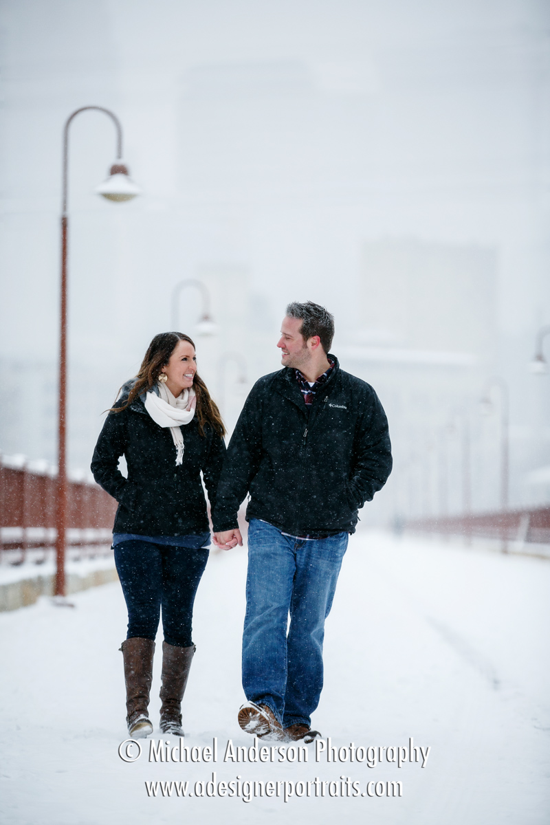 Snowy engagement portraits taken in a snowstorm on the Stone Arch Bridge in Minneapolis, MN.