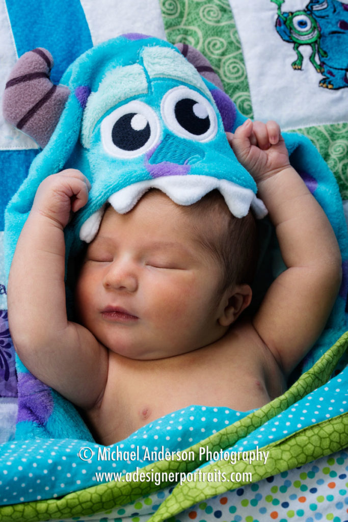 Portrait of an adorable three day old baby boy wearing a Sully comforter from the Disney Pixar movie Monsters Inc.