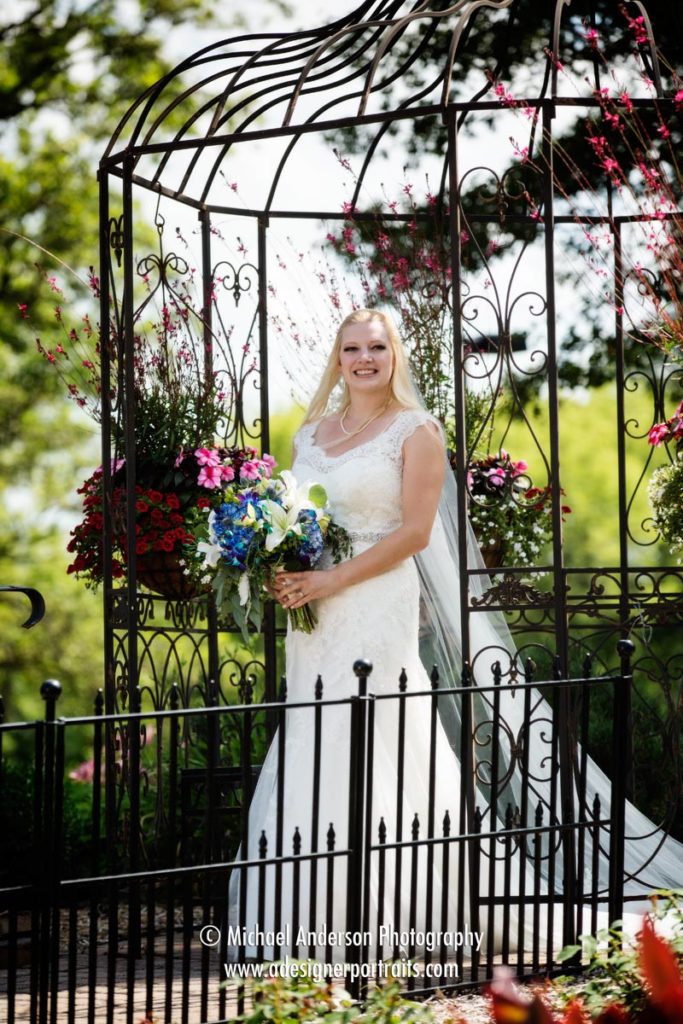 The bride walks through "The Birdcage" on her way to the aisle for her wedding ceremony. Photo taken during her beautiful Panola Valley Gardens wedding ceremony in Lindstrom, MN.