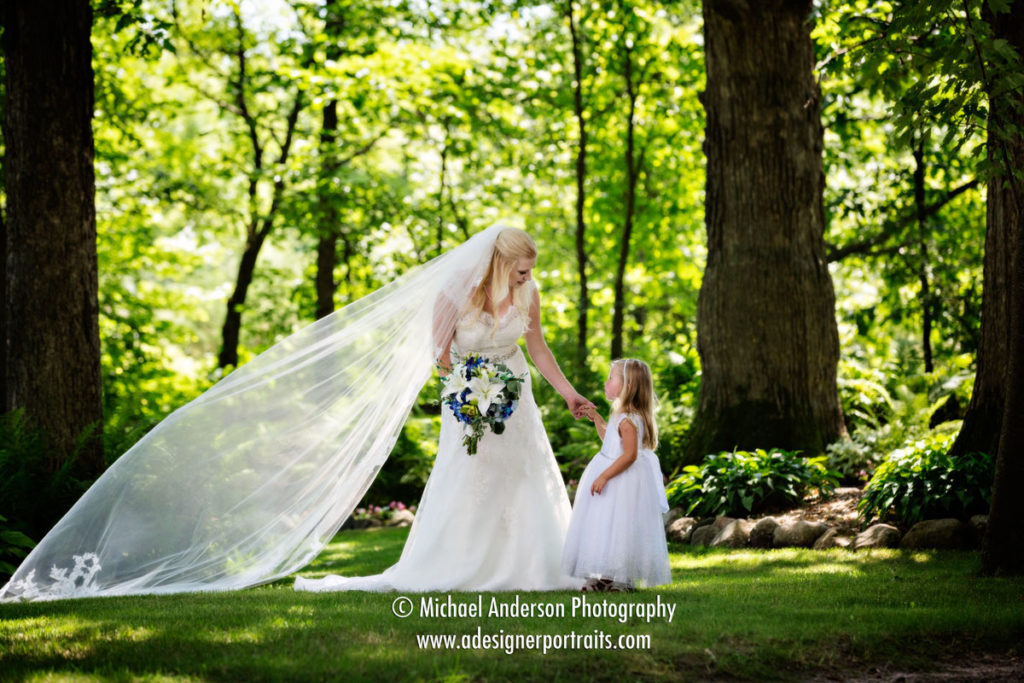 Why Hire a Professional Wedding Photographer. A very pretty portrait of the bride and her flower girl in the woods. Photo taken during their beautiful Panola Valley Gardens wedding ceremony in Lindstrom, MN.