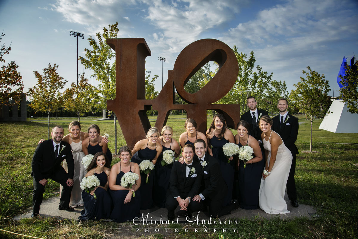 Two grooms and their wedding party at the Love sculpture in the Minneapolis Sculpture Gardens. Image created by the award winning Minneapolis wedding photographers, Michael and Joannie Anderson.