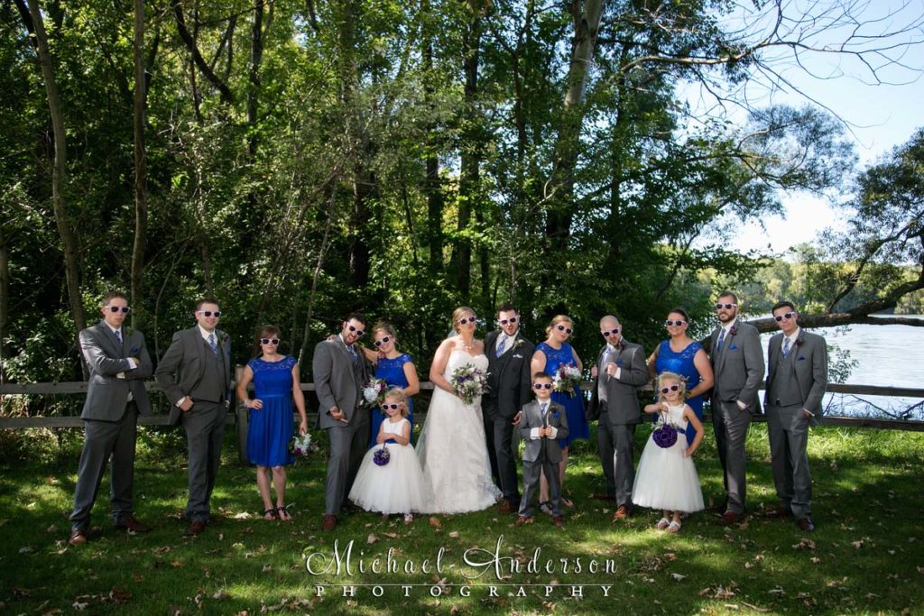 A fun wedding photograph of the whole wedding party wearing sunglasses and goofing off. Image was created at Colby Lake Park in Woodbury, MN.