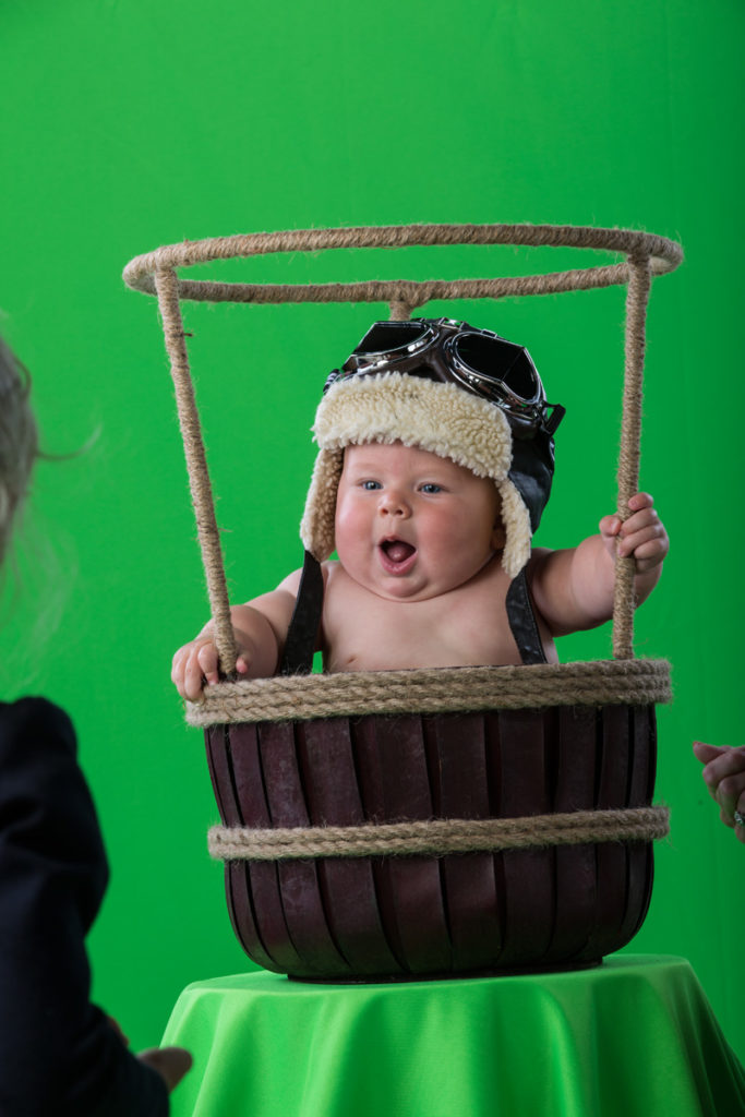 Green screen fantasy baby portrait of an adorable five month old boy in a hot air balloon basket.