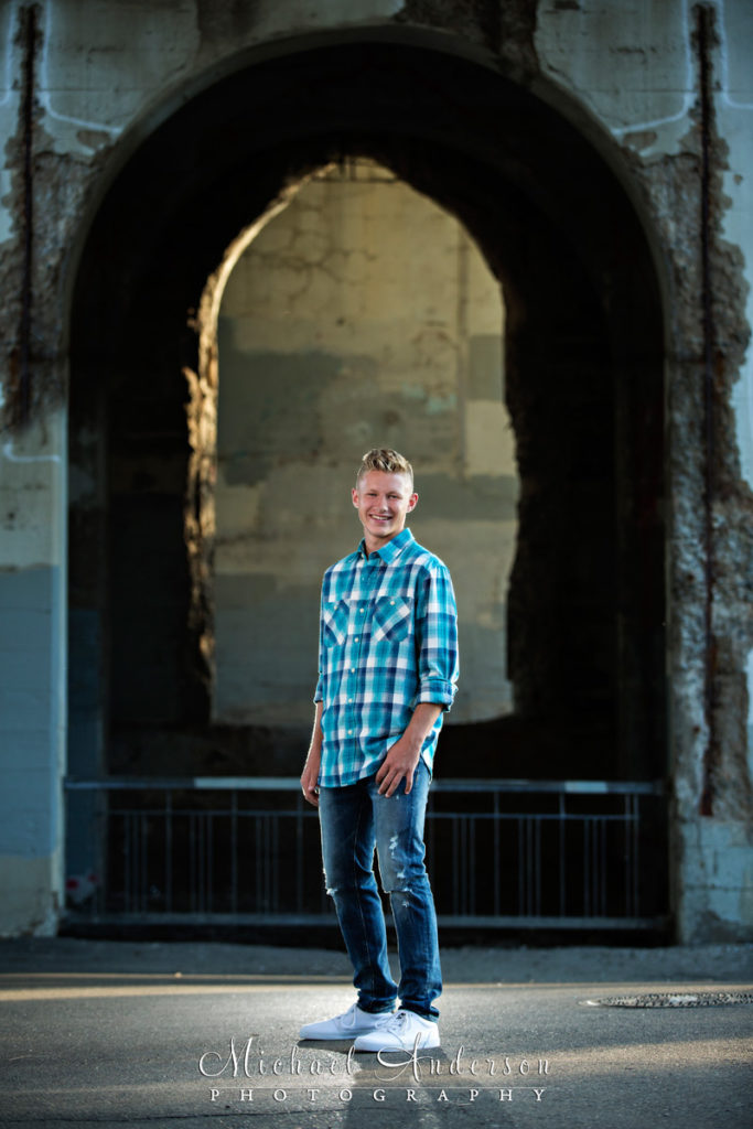 Saint Anthony Main senior portraits of a senior boy standing in an archway under the 3rd Avenue Bridge in Minneapolis, MN.