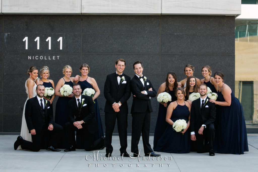 Orchestra Hall wedding photo of the two grooms and their wedding party just outside the front doors of the beautiful building in downtown Minneapolis, MN.