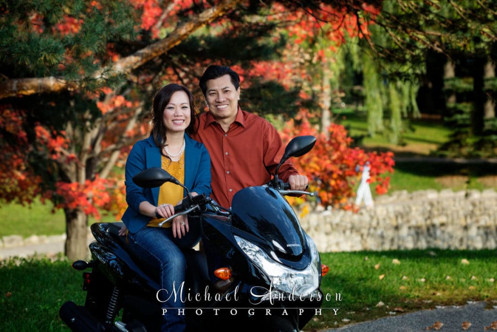 Engagement portrait of a cute couple sitting on a motorcycle in the pretty fall colors. Cute image was taken during their Como Park engagement portraits.