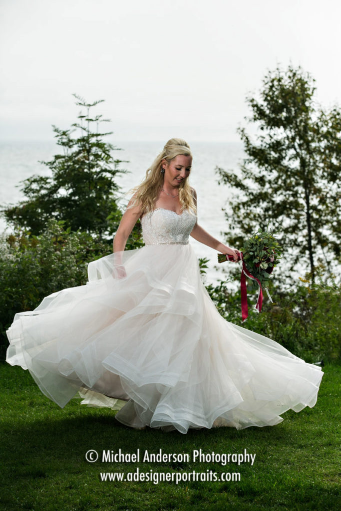 Aleksandra twirls in her pretty wedding dress with Lake Superior in the background. Image was created just before Brycen & Aleksandra's Grand Superior Lodge destination wedding ceremony.