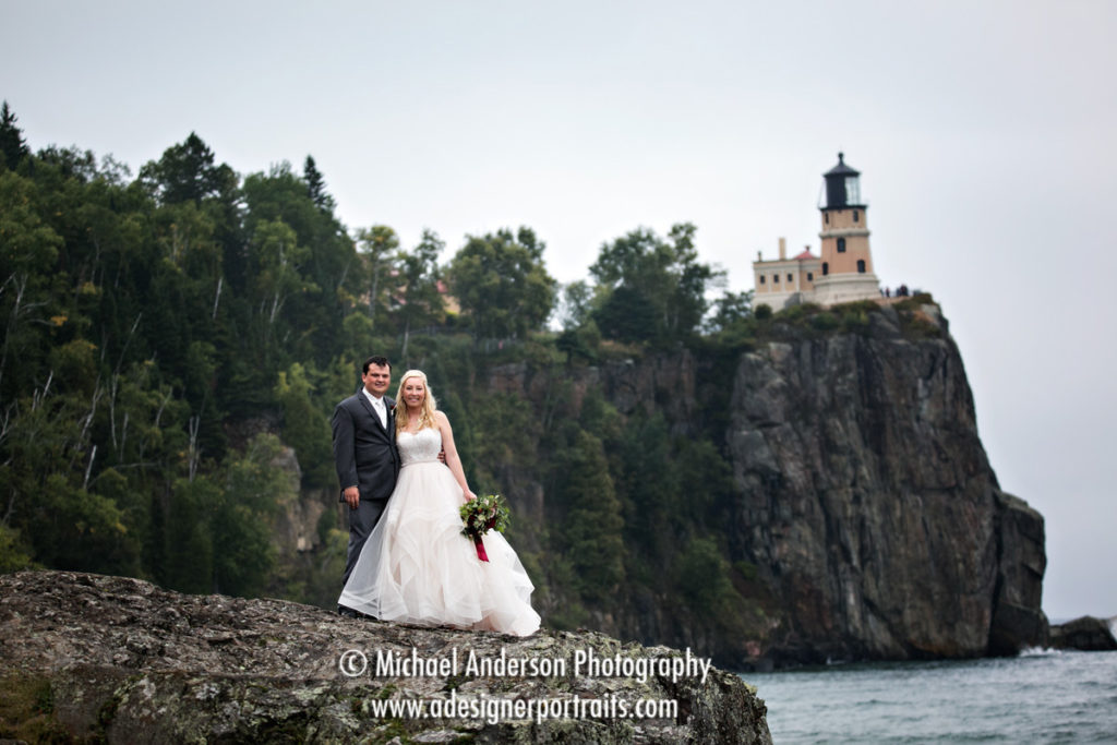 A very pretty, classic wedding portrait of a bride and groom with the famous Split Rock Lighthouse in the background.