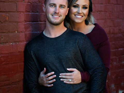 One of Corey and Ashley's fall Stillwater engagement portraits by a red brick wall in downtown Stillwater, MN.
