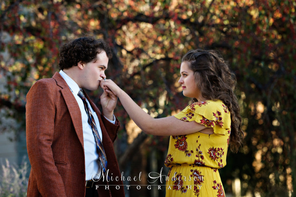 Sam kissing Taylor's hand during their engagement portraits. Image was created on the Minneapolis campus of the University of Minnesota in the fall colors.