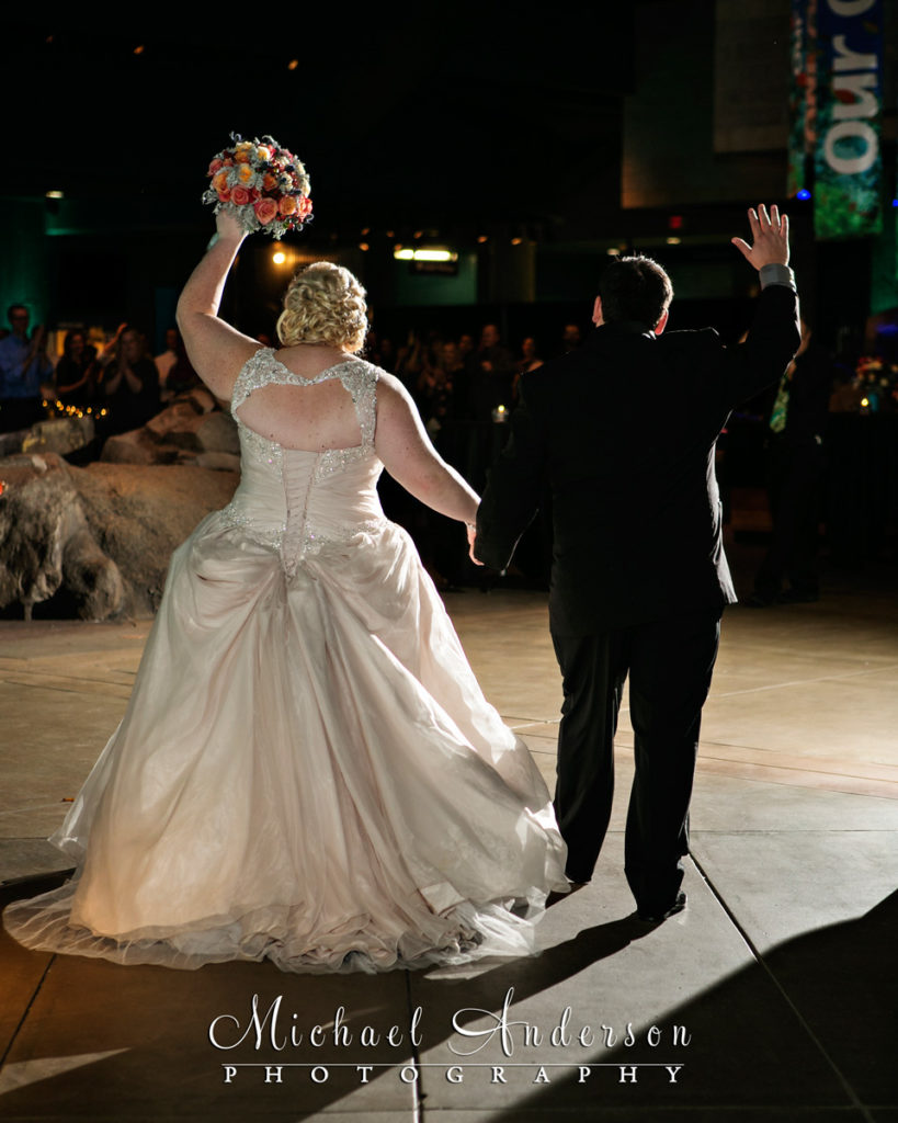 Minnesota Zoo wedding photo of the bride and groom entering their wedding reception to a standing ovation!