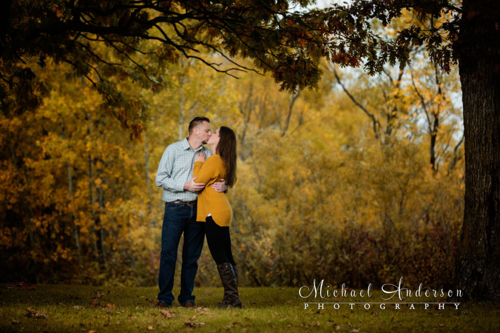 Lochness Park engagement portraits of Dan and Katie kissing in the pretty fall colors under an oak tree.