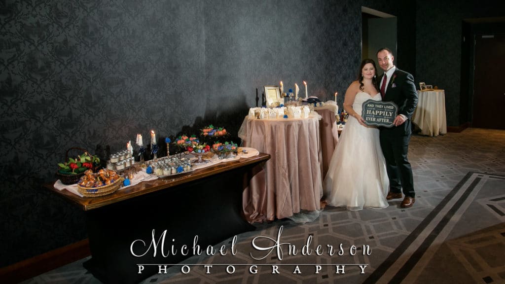 Bride and groom at by their spectacular treat table at their Windows On Minnesota wedding reception.