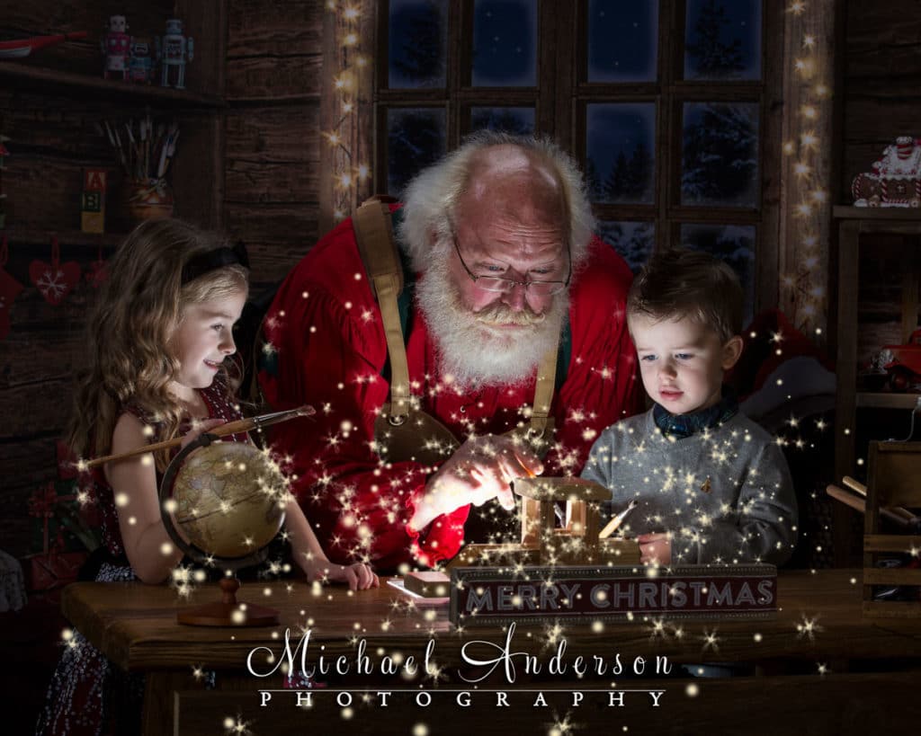 Two cute siblings help Santa paint toys in his workshop. The magical photograph was created during The Santa Experience at Santa's Workshop.