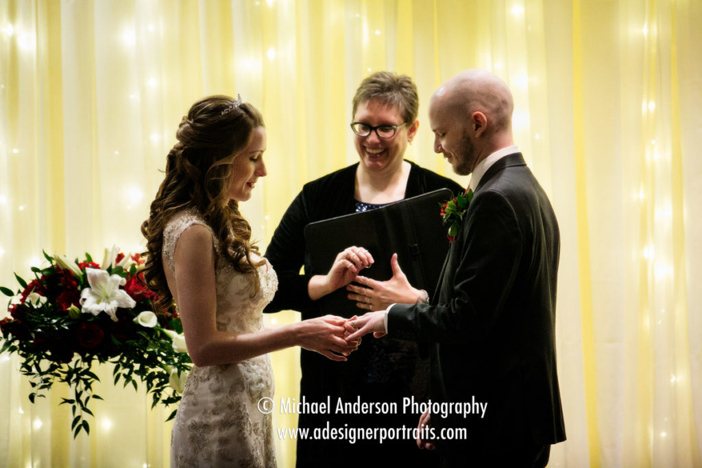 Wedding photography Minneapolis Marriott Northwest. The bride slips the wedding ring on the groom's hand.